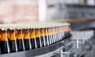 Zelfklevend Fotobehang Automated modern beer bottling factory line with glasses bottles on conveyor. Banner Brewery industry food manufacturing, sunlight © Parilov