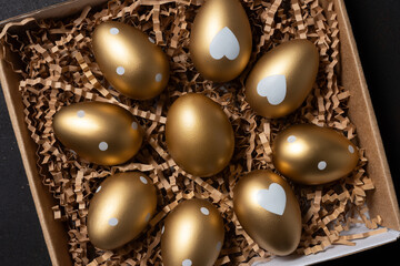 Golden eggs in paper box on a table. Top view.