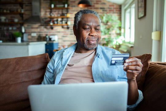 Senior man online shopping with credit card and laptop at home