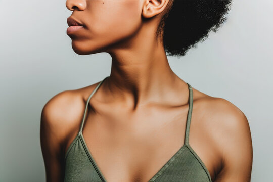Close-up portrait of an African-American woman with afro hair, wearing a green bra, looking sideways against a neutral backdrop