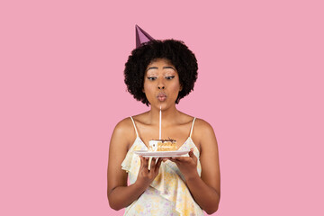 African American woman blowing out birthday candle - 779888371