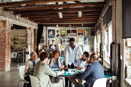 Team meeting with diverse group of professionals discussing project in a modern office