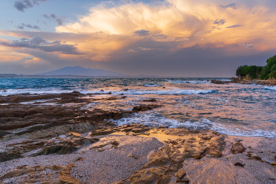A dramatic stormy sky over a rocky coastline in late afternoon light