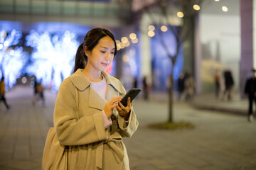 Woman use smart phone in city at night