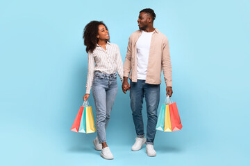 Couple walking and holding shopping bags on blue background