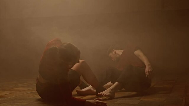 Professional dancers performing dance show. Young man and woman contemporary dancers perform modern choreography elements in smoke, full shot.