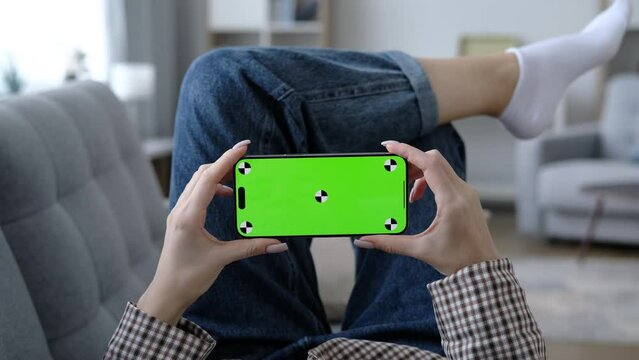 Woman using mobile phone horizontal green screen. Female holding portable gadget close up indoors home living room. Mock-up for tracking. Watching content video blog and surfing internet