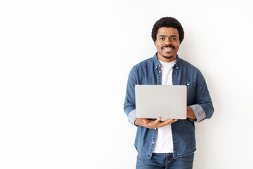 Handsome young black man confidently holding laptop