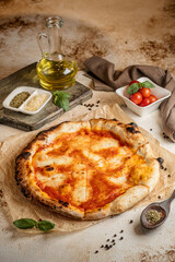 Freshly baked pizza with golden brown crust and bright red tomato sauce. Margarita pizza. A bottle of olive oil. Pizza on a beige background.