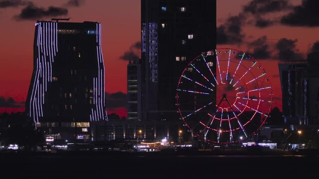 Aerial view of Batumi city in Georgia. Famous touristic coast with ferris wheel and high buildings with cityscape at background