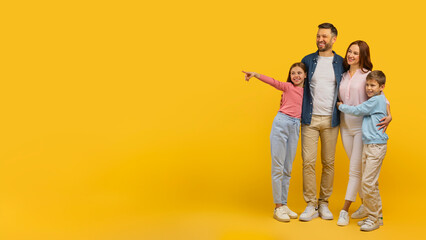 Family pointing to side on yellow backdrop