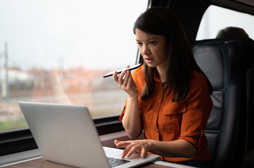 Business woman working while traveling by train using phone and talking
