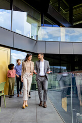 Cheerful Colleagues Exiting a Modern Office Building on a Bright Afternoon