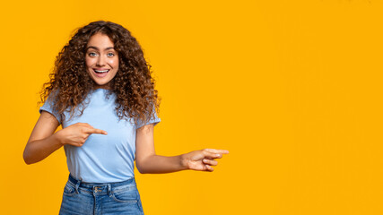 Woman pointing and looking surprised on yellow