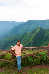 Fototapeta na wymiar A tourist is standing beside railings at perched atop the East Khasi Hills, the Laitlum Canyons that extend over deep valleys, steep cliffs. Hiking retreat offering trails through green meadows.