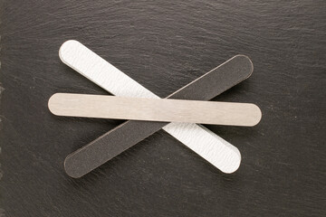 Manicure files with interchangeable files on slate stone, top view.