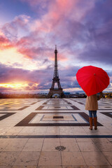 A woman with a heart shaped umbrella watches a romantic sunrise behind the Eiffel Tower of Paris, France - 779927373