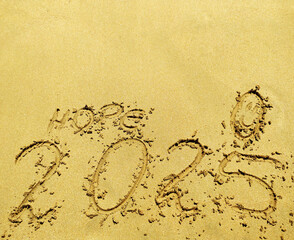 2025 number, word hope and happy face drawned on a beach sand. Abstract background photo to coming New Year 2025