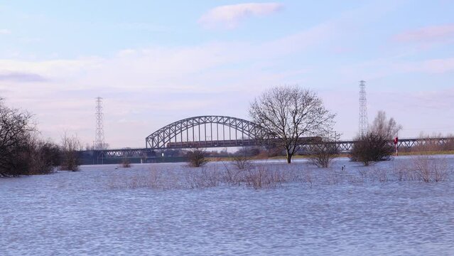 Train rides over bridge over the flooded river Rhine in the Netherlands, in nature park Meinerswijk near Arnhem.