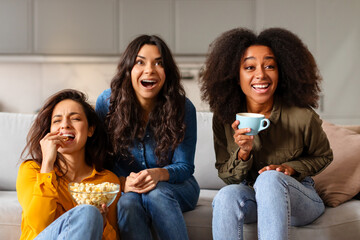 Three friends laughing with coffee and popcorn
