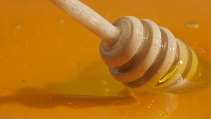 Healthy organic honey. Sweet fresh golden honey on the yellow background with honey dipper scooping...