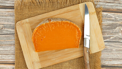 tranche de fromage français : mimolette extra vieille, en gros plan, sur une planche à découper	
