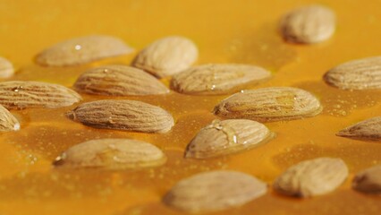 Healthy organic honey. Sweet fresh golden honey on the yellow background, almond nuts in the thick syrup, close up shot.