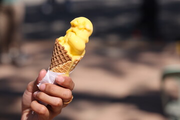 Yellow mango ice cream being held 2 scoops