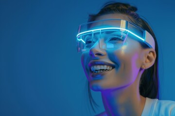 Smiling woman is using futuristic glasses against blue background.