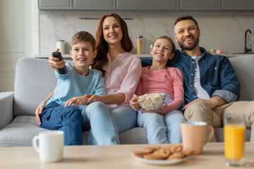 Family watching TV together, smiling joyfully at home