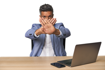 Elegant businessman at desk with laptop doing a denial gesture