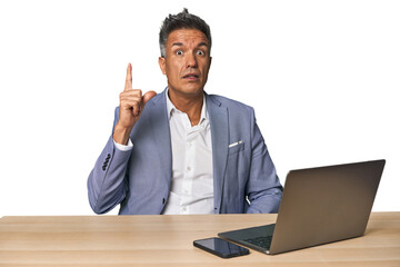 Elegant businessman at desk with laptop having an idea, inspiration concept.