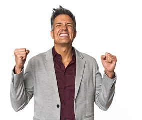 Middle-aged Latino man raising fist after a victory, winner concept.
