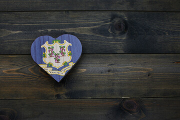 wooden heart with national flag of connecticut state on the wooden background.