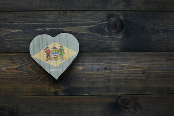 wooden heart with national flag of delaware state on the wooden background.