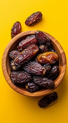 Dried dates in a wooden bowl,  yellow background