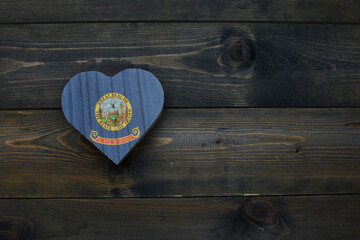 wooden heart with national flag of idaho state on the wooden background.