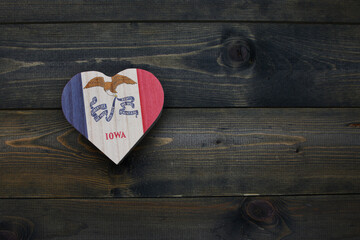 wooden heart with national flag of iowa state on the wooden background.
