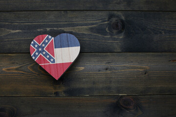 wooden heart with national flag of mississippi state on the wooden background.