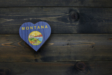 wooden heart with national flag of montana state on the wooden background.