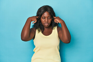 Young african american curvy woman focused on a task, keeping forefingers pointing head.