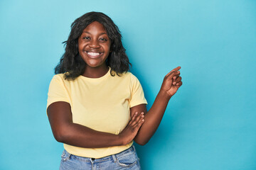 Young african american curvy woman smiling cheerfully pointing with forefinger away.