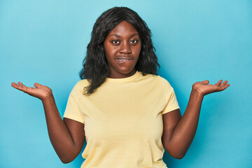 Young african american curvy woman confused and doubtful shrugging shoulders to hold a copy space.