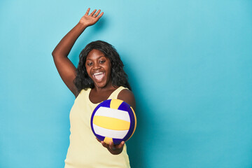 Sporty curvy woman practicing volleyball serves on blue backdrop