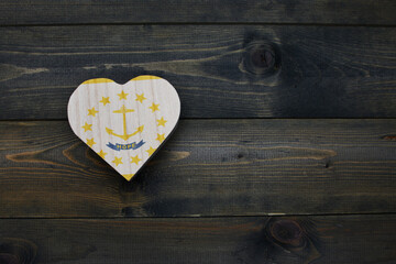 wooden heart with national flag of rhode island state on the wooden background.