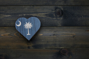 wooden heart with national flag of south carolina state on the wooden background.