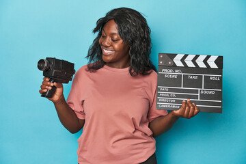 Creative curvy woman with film camera and clapperboard