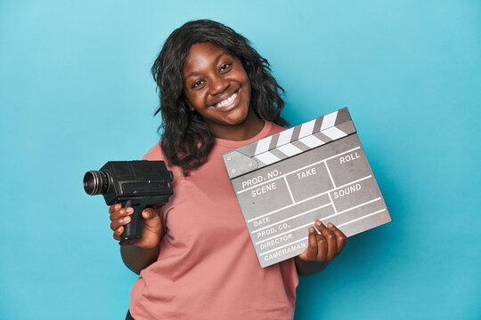 Creative curvy woman with film camera and clapperboard