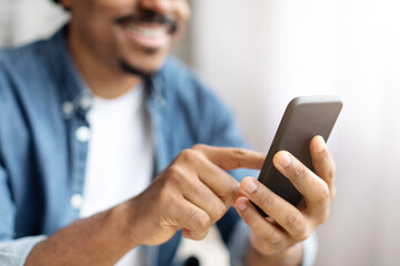 Smiling Black Man Using Smartphone Indoors During Daytime