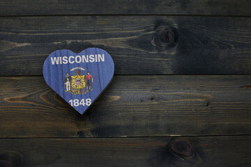 wooden heart with national flag of wisconsin state on the wooden background.